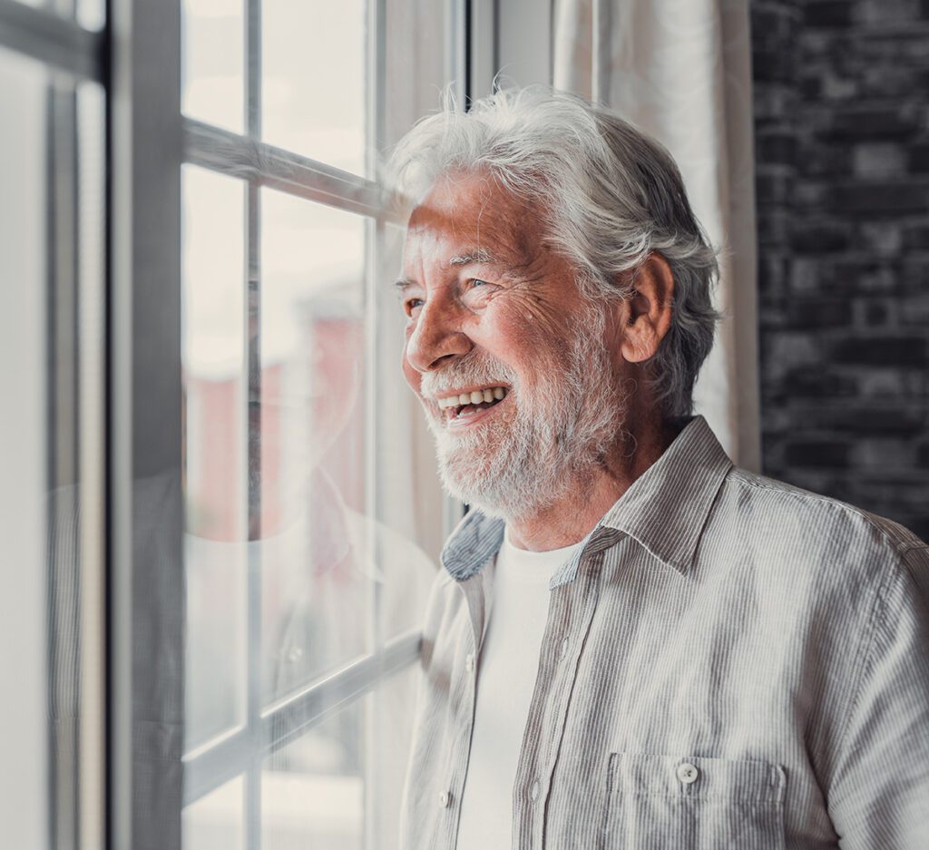 Happy older man looking out of window away with hope