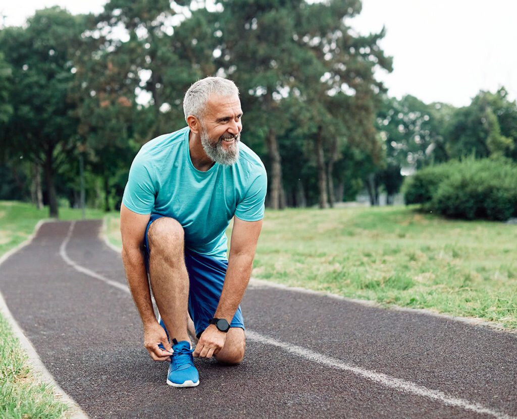 Portrait of a happy active mature or middle aged senior man posing fixing shoelace