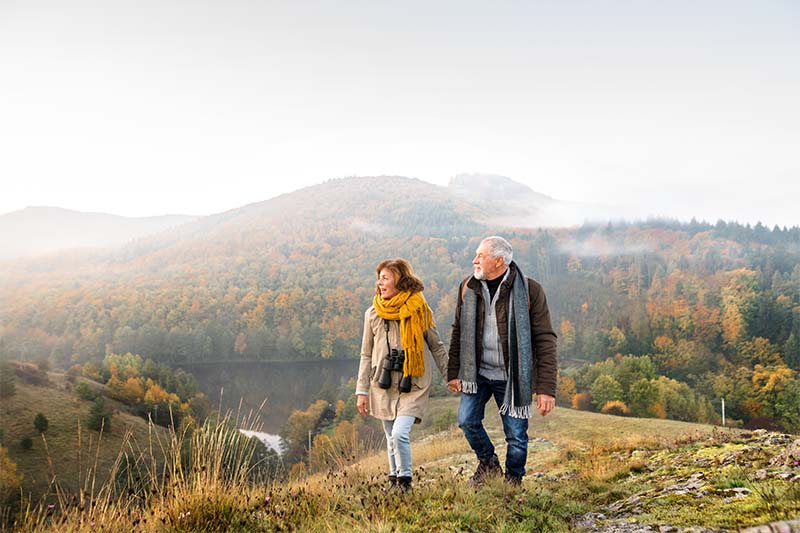 Senior couple on a walk in an autumn nature mobile