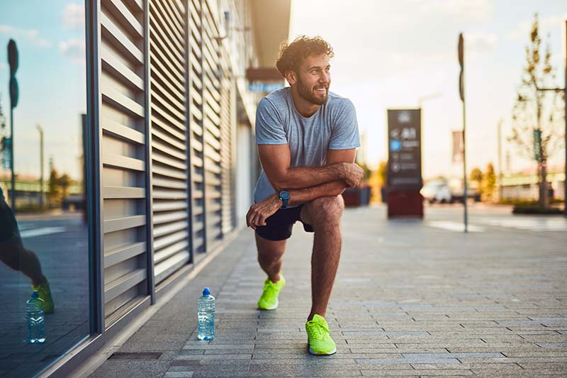 Young man exercising and stretching on a sidewalk